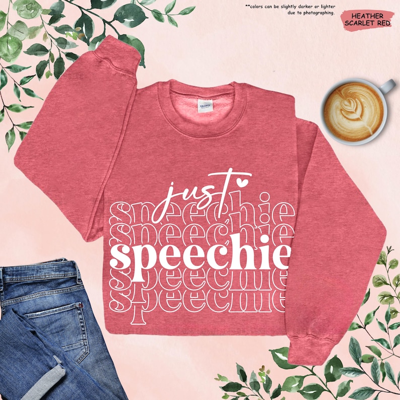 Puede incluir: Una sudadera de color rojo escarlata jaspeado con el texto "just speechie" en blanco. El texto se repite varias veces en un patr&oacute;n apilado.