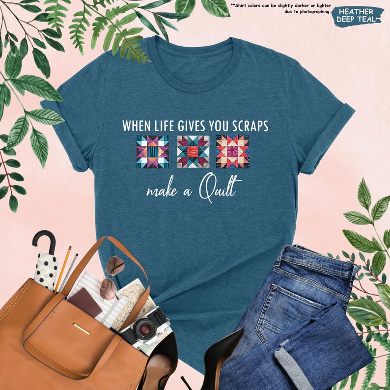 May include: A teal t-shirt with the text "WHEN LIFE GIVES YOU SCRAPS make a Quilt" above three colorful quilt block designs. The shirt is displayed with a brown tote bag, sunglasses, a camera, and blue jeans.