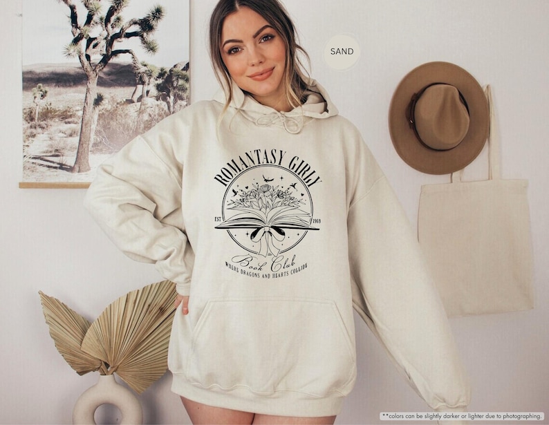 May include: A cream-coloured hoodie with a black graphic of a book with flowers and the text "Romantasy Girl Book Club Where Dragons and Hearts Collide".