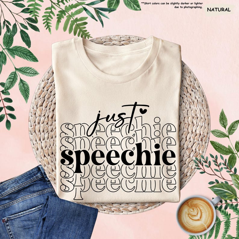 Puede incluir: Una camiseta beige con el texto "just speechie" impreso en negro. El texto se repite varias veces en un patr&oacute;n apilado.