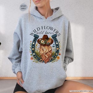 May include: Gray hooded sweatshirt with the text "WILD FLOWERS wild horses" and a graphic of a woman wearing a cowboy hat and a horseshoe.