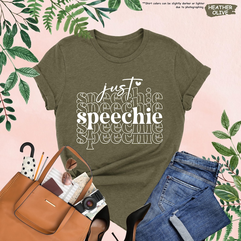 Puede incluir: Una camiseta verde con el texto "just speechie" en letras blancas. El texto est&aacute; apilado y repetido en un estilo retro.
