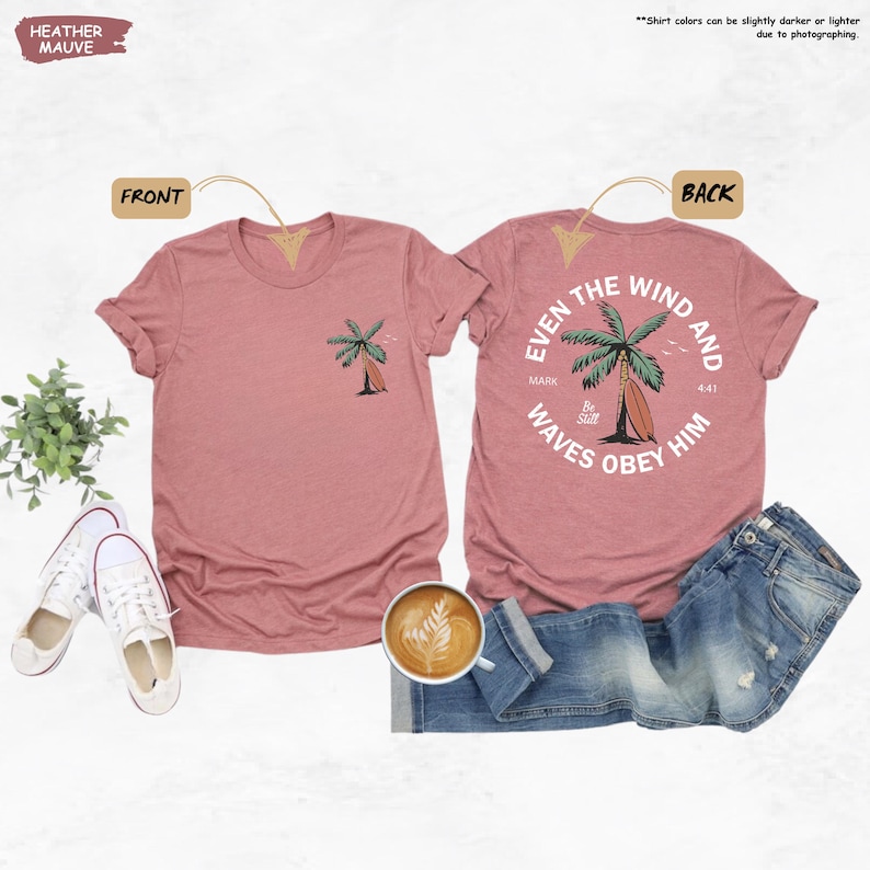 K&ouml;nnte beinhalten: Heather-Mauve-T-Shirts mit Front- und Back-Designs. Die Vorderseite zeigt eine Palmen- und Surfbrett-Grafik. Auf der R&uuml;ckseite steht der Text "Even the wind and waves obey him" mit einer Palmen- und Surfbrett-Grafik. Die Shirts werden mit Jeans und Turnschuhen kombiniert.