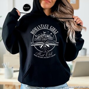 May include: Black hoodie with a white graphic design that says "Romantasy Girl Book Club" with a book, flowers, and stars. The text below the graphic says "Where Dragons and Hearts Collide."