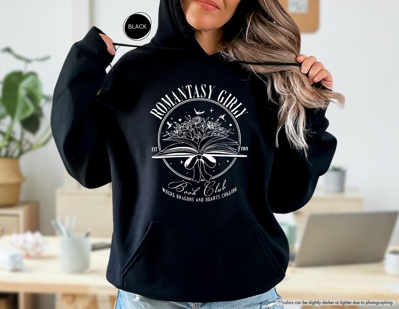 May include: Black hoodie with a white graphic design that says "Romantasy Girl Book Club" with a book, flowers, and stars. The text below the graphic says "Where Dragons and Hearts Collide."