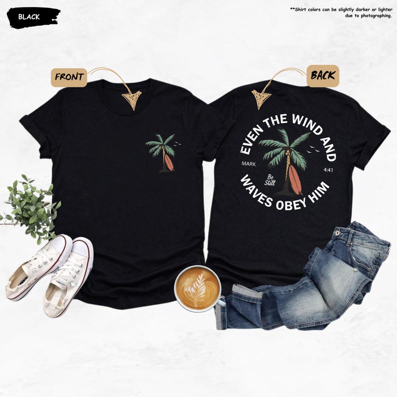 K&ouml;nnte beinhalten: Schwarze T-Shirts mit einem Palmen- und Surfbrett-Motiv. Die Vorderseite des Shirts hat ein kleines Design, w&auml;hrend die R&uuml;ckseite ein kreisf&ouml;rmiges Design mit dem Text "Even the wind and waves obey him" aufweist.