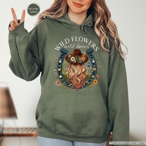 May include: A green hooded sweatshirt with the text "WILD FLOWERS wild horses" and a graphic of a woman with a flower crown and a horseshoe.