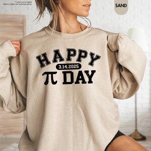 May include: A beige sweatshirt with black text that reads "HAPPY 3.14.2025 PI DAY" in a collegiate font.