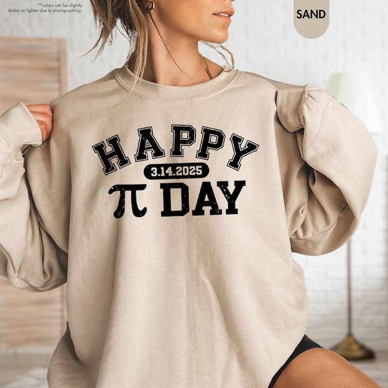 May include: A beige sweatshirt with black text that reads "HAPPY 3.14.2025 PI DAY" in a collegiate font.