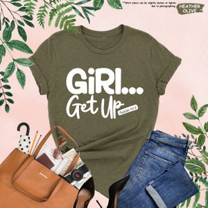 a t - shirt that says girl get up next to a handbag and purse