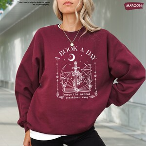a woman wearing a maroon sweatshirt and black pants