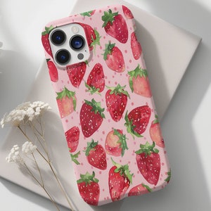 May include: A pink phone case featuring a pattern of red strawberries. The case has a camera lens cutout and a white background.