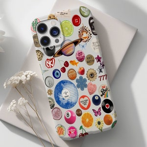 May include: A white phone case with a colorful collage of various designs, including a planet, cherries, a 777 slot machine, a red heart, a blue eye, and a butterfly. The case also features a camera lens cutout and a text that says "Hot Shit".