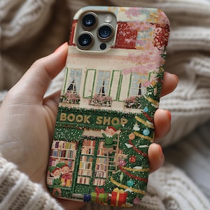 May include: A phone case with a festive design depicting a book shop decorated for Christmas. The illustration shows a green shop front with the words "BOOK SHOP", a Christmas tree, and elves. The case has a charming, storybook style.