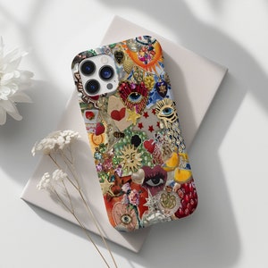 mosaic phone case with elements like jewels, rhinesttones, eyes, pearls, sunm stars and hearts. the phone sits on top of plain white notebook thats framed beautifully with white daisy flowers