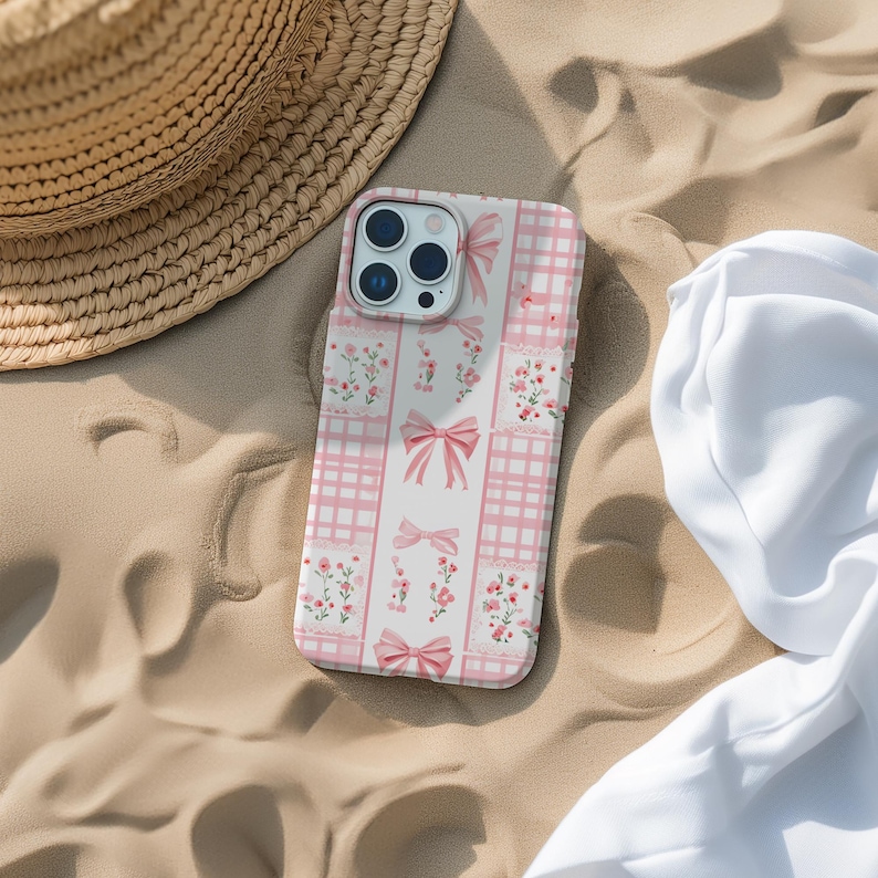 May include: A pink and white phone case with a checkered pattern and pink bows. The case has a floral design with small pink flowers.