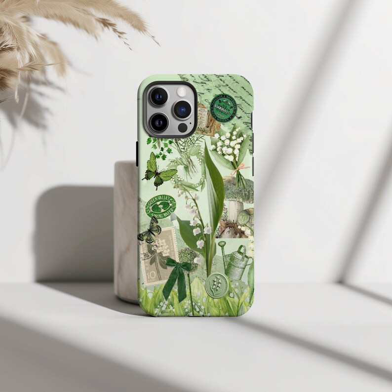 May include: A green and white phone case with a floral design featuring lilies of the valley, butterflies, and a watering can. The case has a vintage aesthetic with a green and white color scheme.