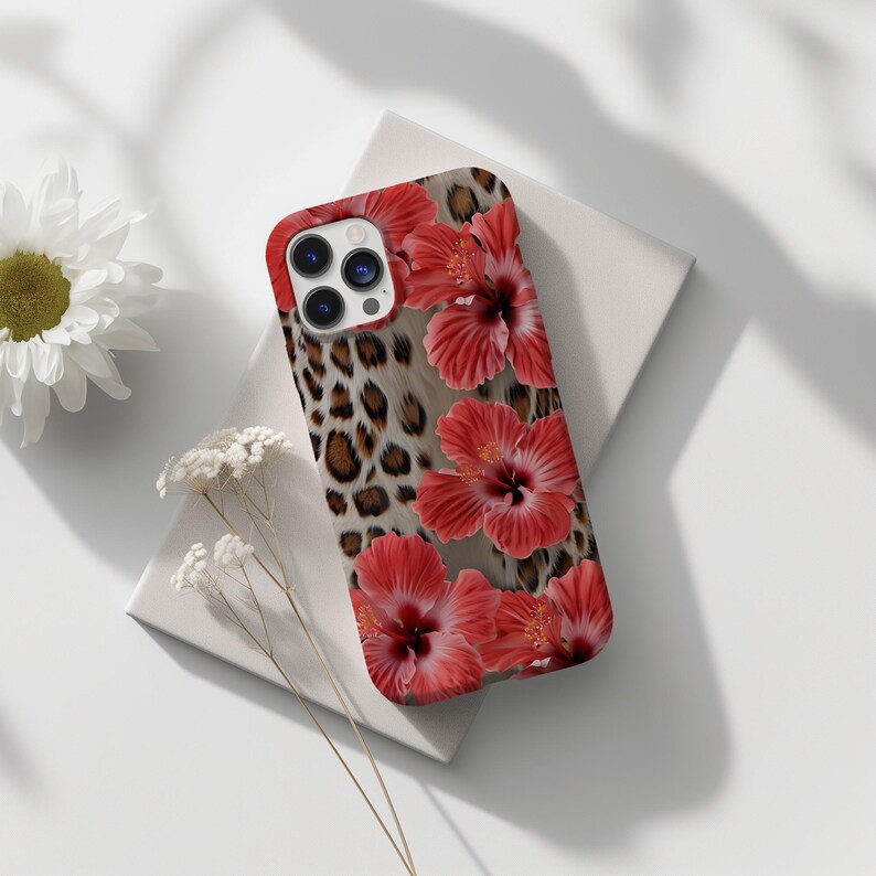May include: A phone case with a leopard print background and red hibiscus flowers. The case has a cutout for the camera lens.