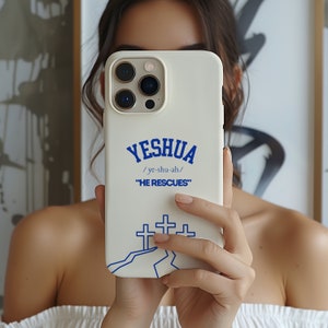 May include: White iPhone case with a blue design. The design features the word "YESHUA" with the pronunciation "/ye-shu-ah/" and the phrase "HE RESCUES". There are three blue crosses on a white mountain in the design.