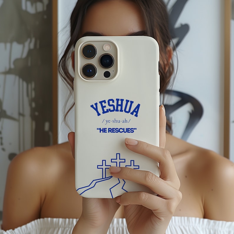 May include: White iPhone case with a blue design. The design features the word "YESHUA" with the pronunciation "/ye-shu-ah/" and the phrase "HE RESCUES". There are three blue crosses on a white mountain in the design.