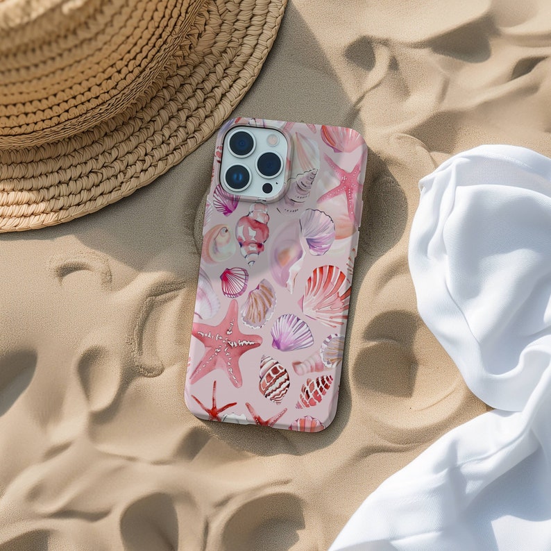 May include: A pink phone case with a watercolor design of seashells and starfish. The case has a camera lens cutout and a white background.