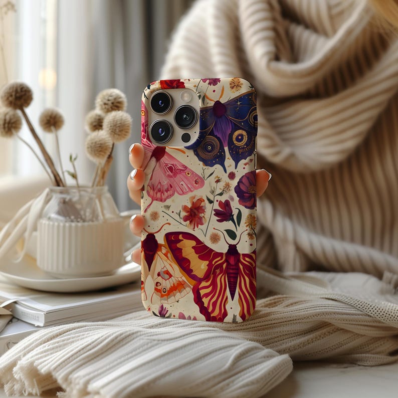 May include: A phone case featuring a colourful floral and butterfly design. The case showcases a variety of butterflies in shades of pink, purple, and orange, as well as flowers in shades of pink, yellow, and red. The case is made from a durable material and is designed to protect your phone from scratches and bumps.
