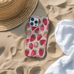 May include: A pink phone case featuring a pattern of red strawberries and white dots. The case is designed for an iPhone.