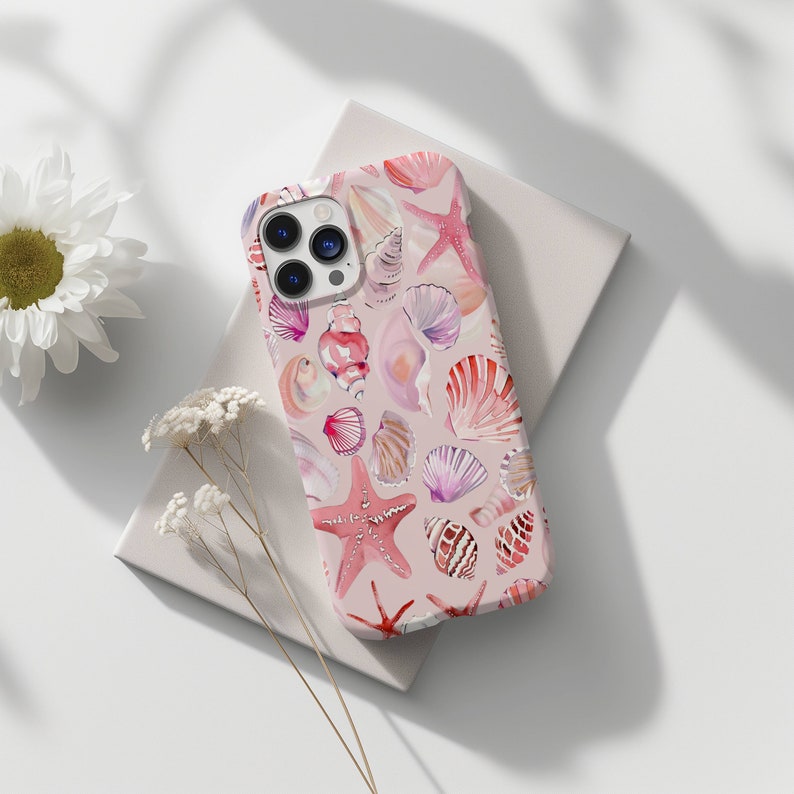 May include: A pink phone case with a pattern of seashells and starfish. The case is designed for an iPhone.