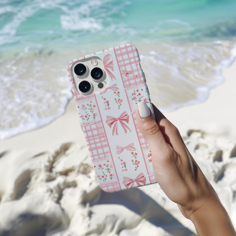 May include: A pink and white phone case with a checkered pattern and pink bows. The case has a floral design with small pink flowers.