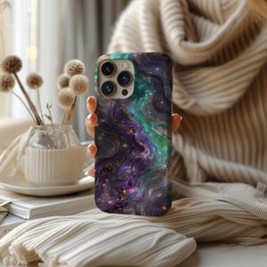 May include: A phone case with a galaxy-like design featuring swirling purple, green, and blue colours with gold accents.