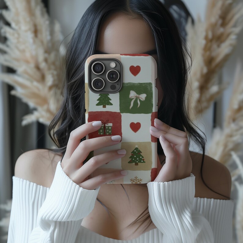 A woman is holding a phone with a colorful Christmas-themed case, taking a selfie in front of a festive background.