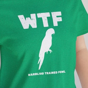 May include: Green t-shirt with white text that says "WTF Warbling Trained Fowl" and a white silhouette of a parrot.