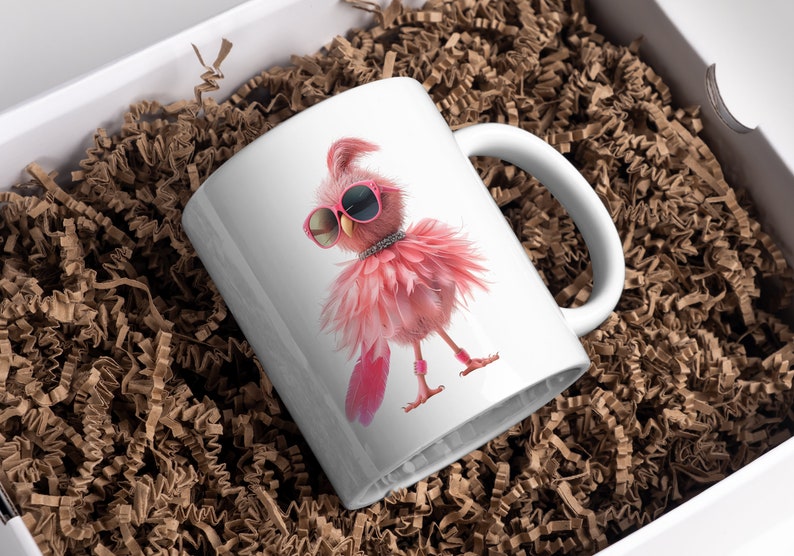 May include: White ceramic mug with a pink flamingo wearing sunglasses and a sparkly necklace. The flamingo is standing on one leg and has its wings spread out. The mug is in a box with brown packing paper.