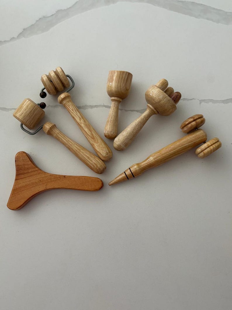 May include: A collection of wooden massage tools. The tools vary in shape and size, including rollers, a small cup, and a pointed tool. The wood has a natural, light brown color. These tools are designed for massage and bodywork, potentially for relaxation and therapeutic purposes.