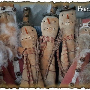 May include: A group of seven handmade primitive Christmas ornaments. The ornaments are made of fabric and have a rustic, vintage look. They are decorated with bells, buttons, and other embellishments. The ornaments are all different shapes and sizes, and they are all unique. The ornaments are arranged in a row on a wooden surface. The text "Peach Bottom Primitives" is visible in the upper right corner of the image.