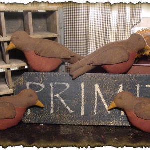 Peut inclure: Quatre oiseaux en tissu de style primitif de couleur brune et rouge. Les oiseaux sont assis sur une pancarte en bois qui dit "PRIMITIVE".