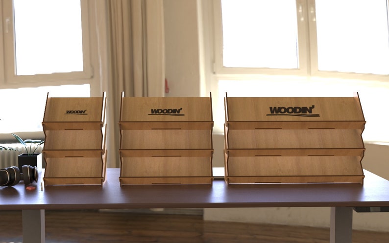 May include: Three wooden display stands with three shelves each. The stands are made of light brown wood and have the word "WOODIN'" printed on the top shelf.