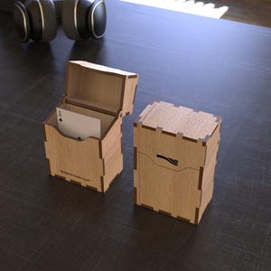 May include: Two wooden card cases, one open and one closed, sit on a dark surface. The open case displays a playing card. The cases are made of light-colored wood and feature a decorative design. The text "WOODEN CARD CASE" is visible on the open case.