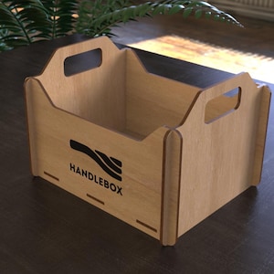May include: A light brown wooden Handlebox with cut-out handles. The box has a rectangular shape with a logo and the word "HANDLEBOX" printed in black on the front. The box is made of light-colored wood.