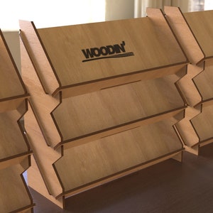 May include: A set of four wooden display stands with three shelves each. The stands are made of light brown wood and have a black "WOODN'" logo on the top shelf.