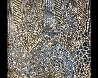 Paillettes extensibles dans 4 sens sur résille dorée sur résille noire. Tissu 54 po. Vendu par mètre. Mariage, bal de promo, robes, lingerie, reconstitution historique.