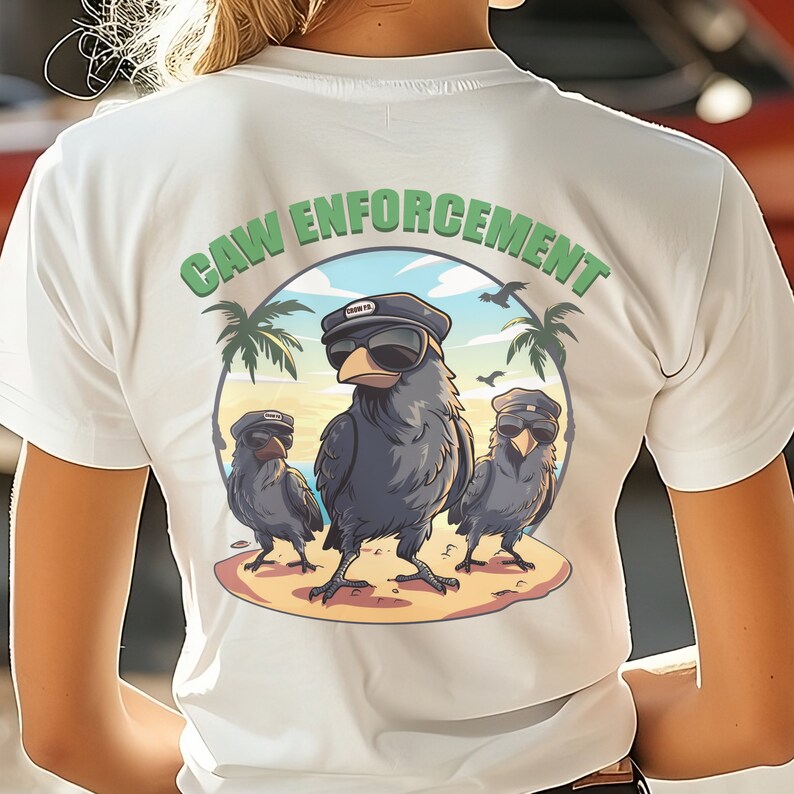 以下が含まれることがあります： 白いTシャツに、緑色の円形のグラフィックが描かれており、「CAW ENFORCEMENT」と書かれています。円の中には、サングラスと帽子をかぶった3羽の漫画のクロウがいます。クロウたちは、ヤシの木のあるビーチに立っています。