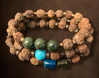 May include: A triple-strand bracelet with brown wooden beads, green and blue gemstone beads, and gold metal accents.