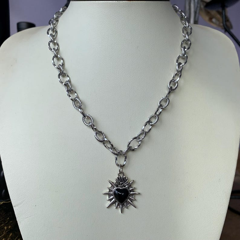 Our Thorn Heart Necklace, a stunning gothic necklace crafted with care and precision. This goth chain necklace features a striking black or red heart pendant wrapped in intricate thorn details, perfectly embodying alternative and edgy style.
Measuring approximately 16 inches in length with an Magnetic clasp. The pendant itself is compact yet bold, making a unique statement piece that enhances any gothic or punk-inspired outfit.