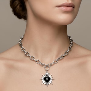 Puede incluir: Una taza de cerámica blanca con un asa negra y el texto "But First, Coffee" en negro, con una fuente de estilo manuscrito. La taza está sobre una superficie blanca.