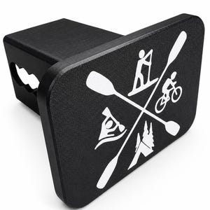 Pode incluir: Tampa de engate de reboque de metal preto com gráficos brancos de atividades ao ar livre, incluindo stand-up paddle, caiaque, ciclismo e caminhadas. A tampa tem uma superfície texturizada.