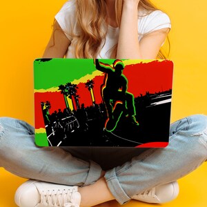 May include: A laptop computer with a colorful design featuring a silhouette of a person skateboarding. The design includes green, red, and yellow colors. The laptop is open and sitting on the lap of a person wearing blue jeans.