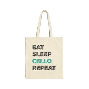 May include: A beige tote bag with black text that reads "Eat Sleep Cello Repeat" in a vintage style font. The word "Cello" is in a teal blue colour.