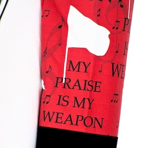 May include: Red fabric with a white silhouette of a flag and musical notes. The text "MY PRAISE IS MY WEAPON" is printed in black.