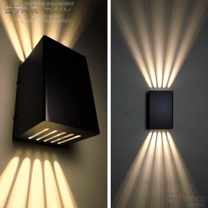 Puede incluir: Aplique de pared exterior negro con iluminación multihaz ajustable. La aplique tiene una forma cuadrada y un diseño moderno. Los haces de luz se dirigen hacia arriba y hacia afuera, creando un efecto dramático.